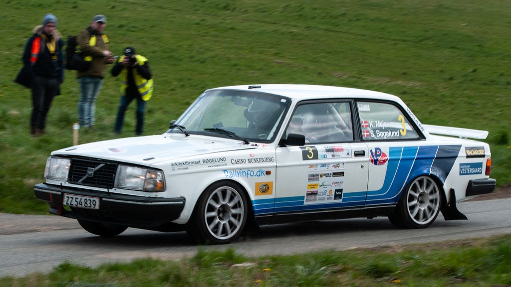 Et par fotografer og en official i DIS Rally Yding passeres her af Kurt Mejer og Steen Bøgelund i den hurtige Volvo 242 Turbo
(Foto: rallypics.dk / Viggo Johansen)